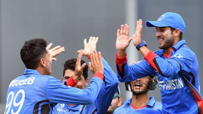 Mujeeb Zadran of Afghanistan (L) is congratulated by team mates after dismissing Jakob Bhula of New Zealand