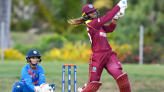 Hayley Matthews (R) of Windies hits 6 as Tanya Bhatia (L) of India watch during a warm-up match at Coolidge Cricket Ground on November 4, 2018 in Coolidge, Antigua and Barbuda.