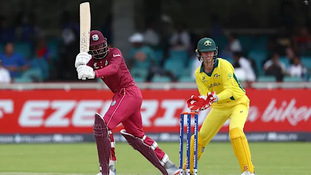 Nyeem Young of West Indies hits the ball towards the boundary, as Patrick Rowe of Australia looks on during the ICC U19 Cricket World Cup Group B match between Australia and West Indies at De Beers Diamond Oval on January 18, 2020.