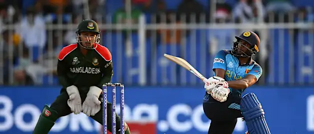 Bhanuka Rajapaksa of Sri Lanka plays a shot as Nurul Hasan of Bangladesh looks on during the ICC Men's T20 World Cup match between Sri Lanka and Bangladesh at Sharjah Cricket Stadium on October 24, 2021 in Sharjah, United Arab Emirates.