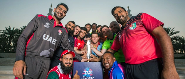 The 14 captains pose with the tournament trophy in front of the Grand Mosque