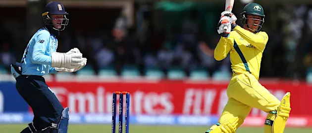 Mackenzie Harvey of Australia hits the ball towards the boundary, as Jordan Cox of England looks on during the ICC U19 Cricket World Cup Group B match between Australia and England at De Beers Diamond Oval on January 23, 2020 in Kimberley, South Africa.