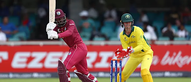 Nyeem Young of West Indies hits the ball towards the boundary, as Patrick Rowe of Australia looks on during the ICC U19 Cricket World Cup Group B match between Australia and West Indies at De Beers Diamond Oval on January 18, 2020.