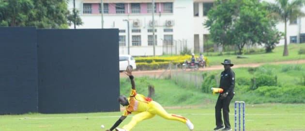Uganda's Charles Waiswa is in a full stretch as he tries to stop a ball off his own bowling