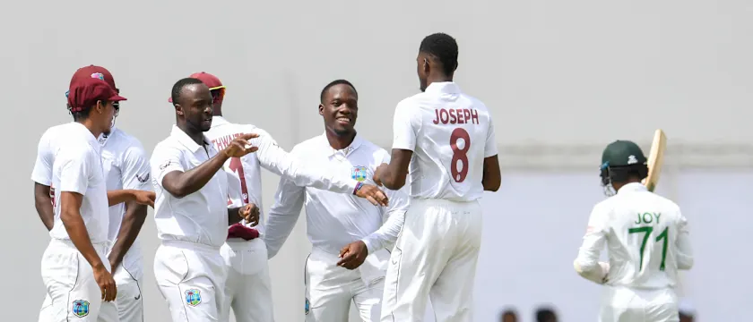 Kemar Roach and Nkrumah Bonner of West Indies celebrate with teammate Alzarri Joseph the dismissal of Mahmudul Hasan Joy