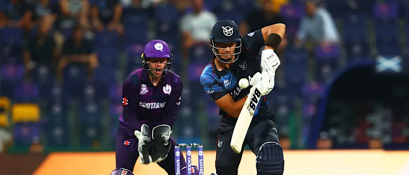 JJ Smit of Namibia plays a shot as Matthew Cross of Scotland looks on during the ICC Men's T20 World Cup match between Scotland and Namibia at Sheikh Zayed stadium on October 27, 2021 in Abu Dhabi, United Arab Emirates.