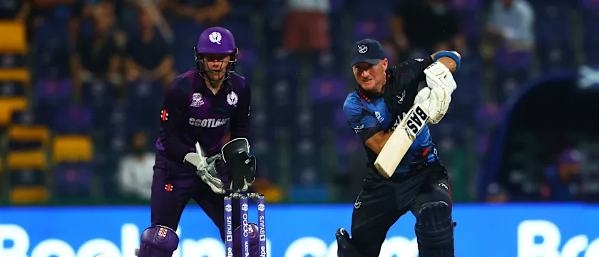Craig Williams of Namibia plays a shot as Matthew Cross of Scotland looks on during the ICC Men's T20 World Cup match between Scotland and Namibia at Sheikh Zayed stadium on October 27, 2021 in Abu Dhabi, United Arab Emirates.