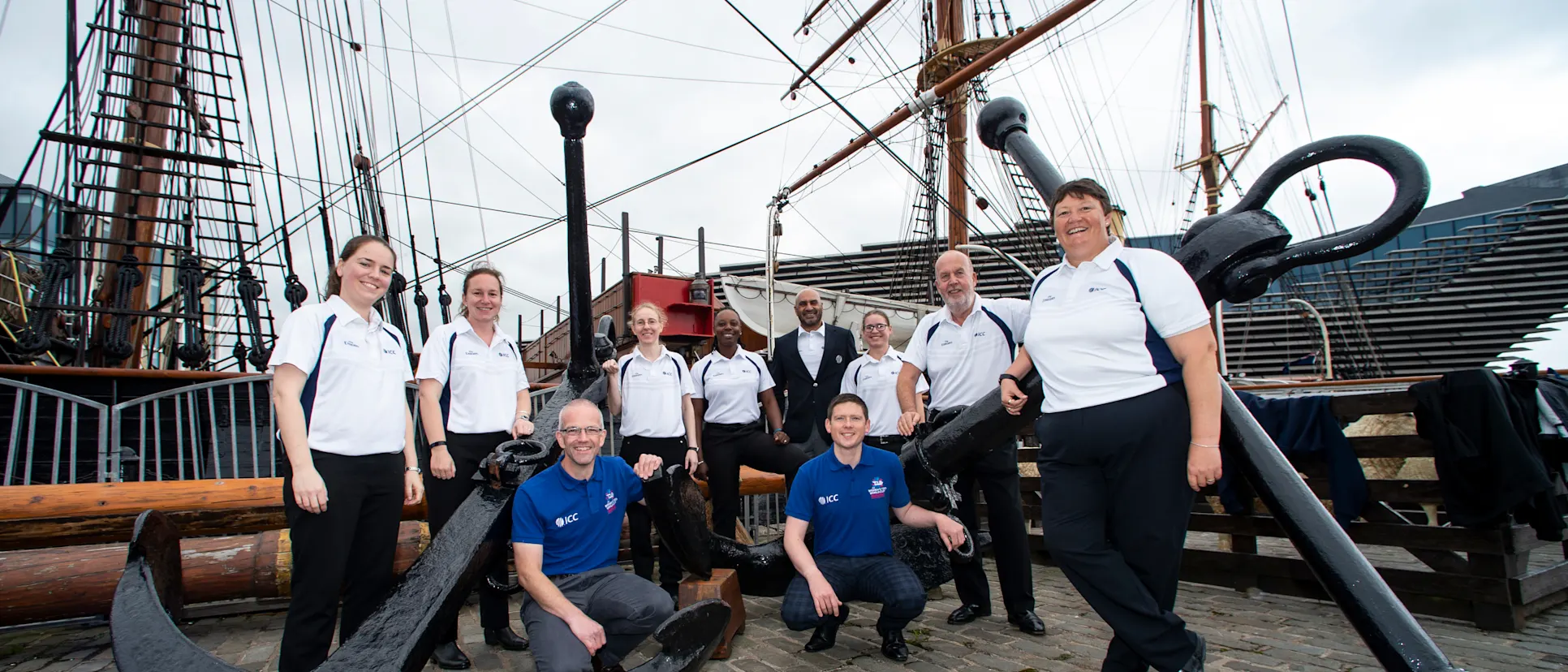 Logo of Women's Qualifier Tournament Officials L to R: standing - Eloise Sheridan, Claire Polosak, Kim Cotton, Jacqueline Williams, Graeme Labrooy, Lauren Agenbag, Denis Burns. Sue Redfern, Squatting - Ian Potts and Willie Ferguson, match liaison officials.