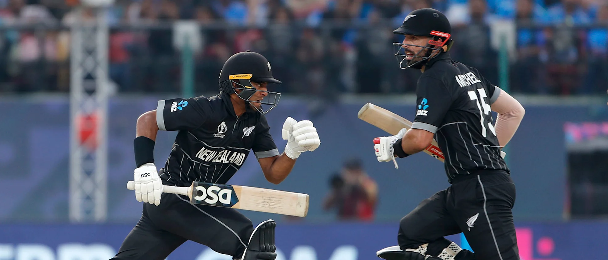 Logo of Daryl Mitchell (L) and Rachin Ravindra of New Zealand run between the wicket during the ICC Men's Cricket World Cup India 2023 match between India and New Zealand