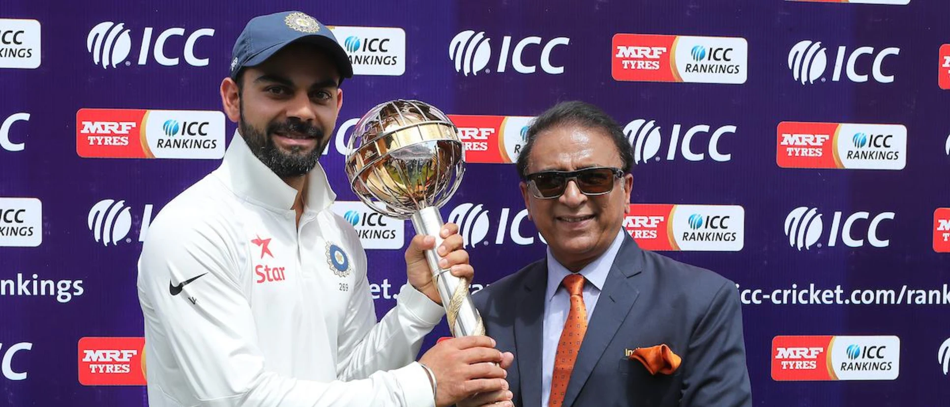 Logo of Virat Kohli poses with the mace along with Sunil Gavaskar