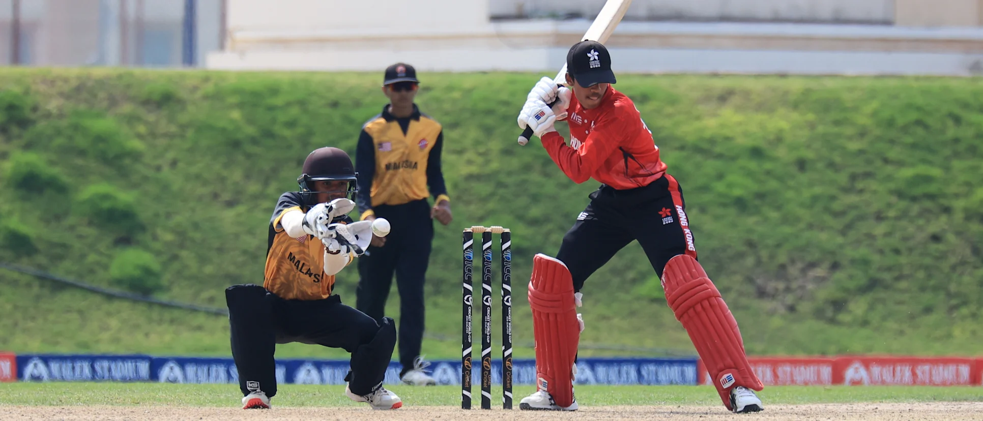 Logo of Hong Kong and Malaysia in action in the ICC U19 Men's CWC Asia Division 1 Qualifier 2023