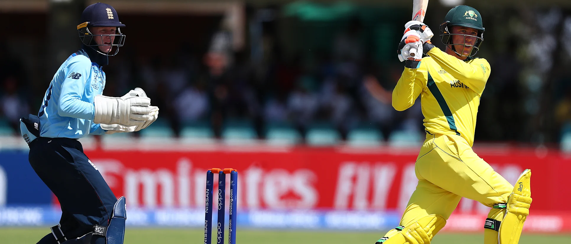 Logo of Mackenzie Harvey of Australia hits the ball towards the boundary, as Jordan Cox of England looks on during the ICC U19 Cricket World Cup Group B match between Australia and England at De Beers Diamond Oval on January 23, 2020 in Kimberley, South Africa.