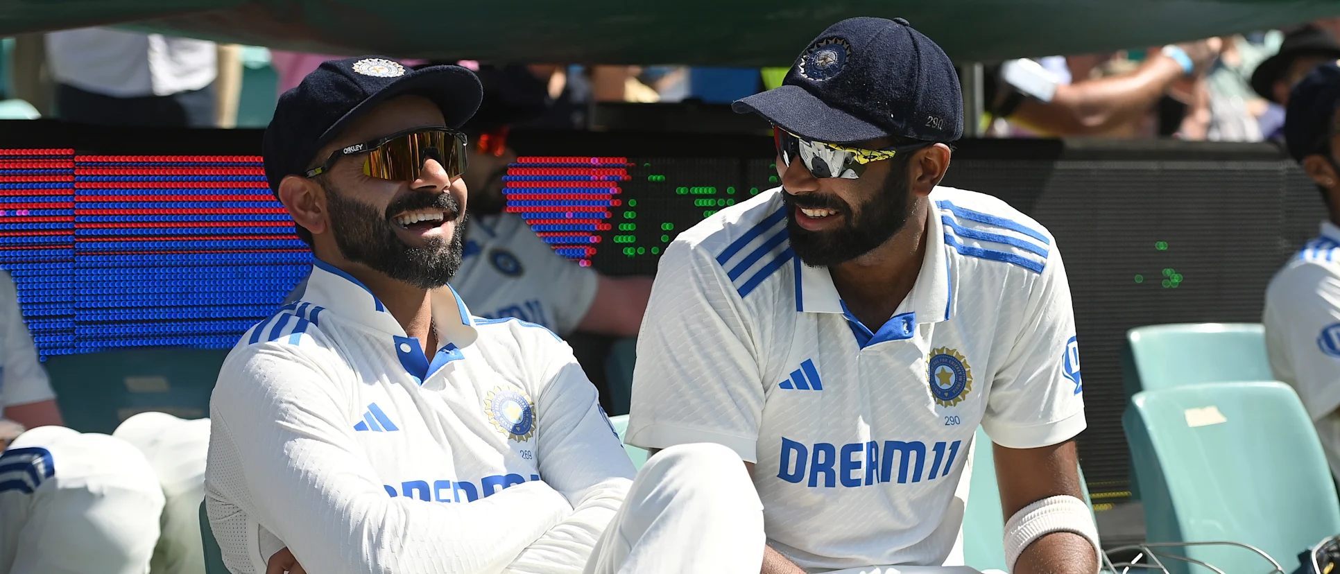 Logo of Virat Kohli and Jasprit Bumrah sharing a laugh in the dugout