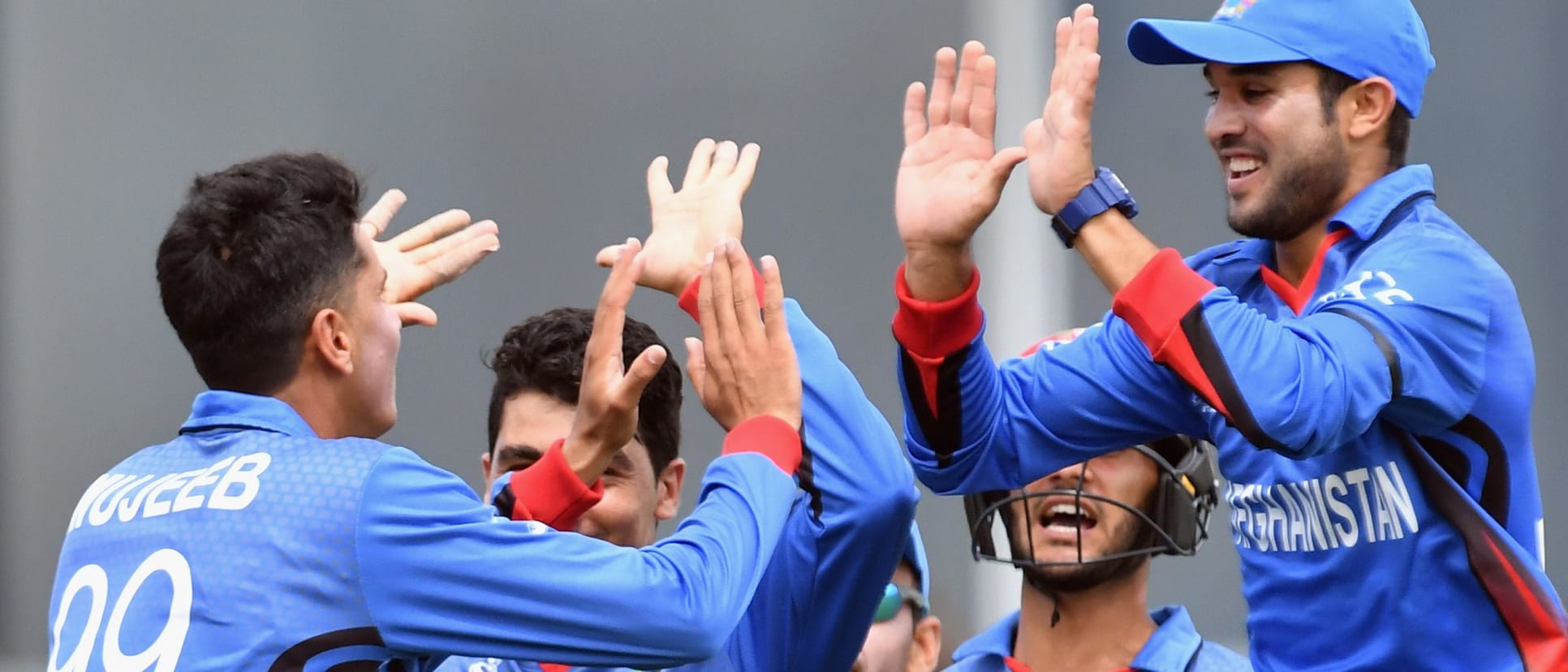 Mujeeb Zadran of Afghanistan (L) is congratulated by team mates after dismissing Jakob Bhula of New Zealand