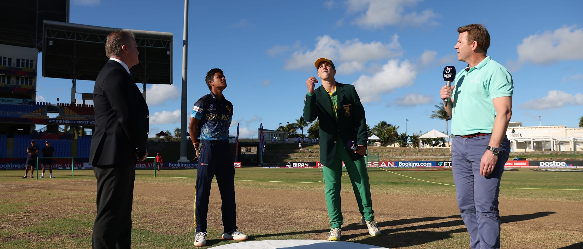 George Van Heerden of South Africa tosses the coin at the coin toss as Dunith Wellalage of Sri Lanka looks on ahead of the ICC U19 Men's Cricket World Cup match between South Africa and Sri Lanka at Sir Vivian Richards Stadium.