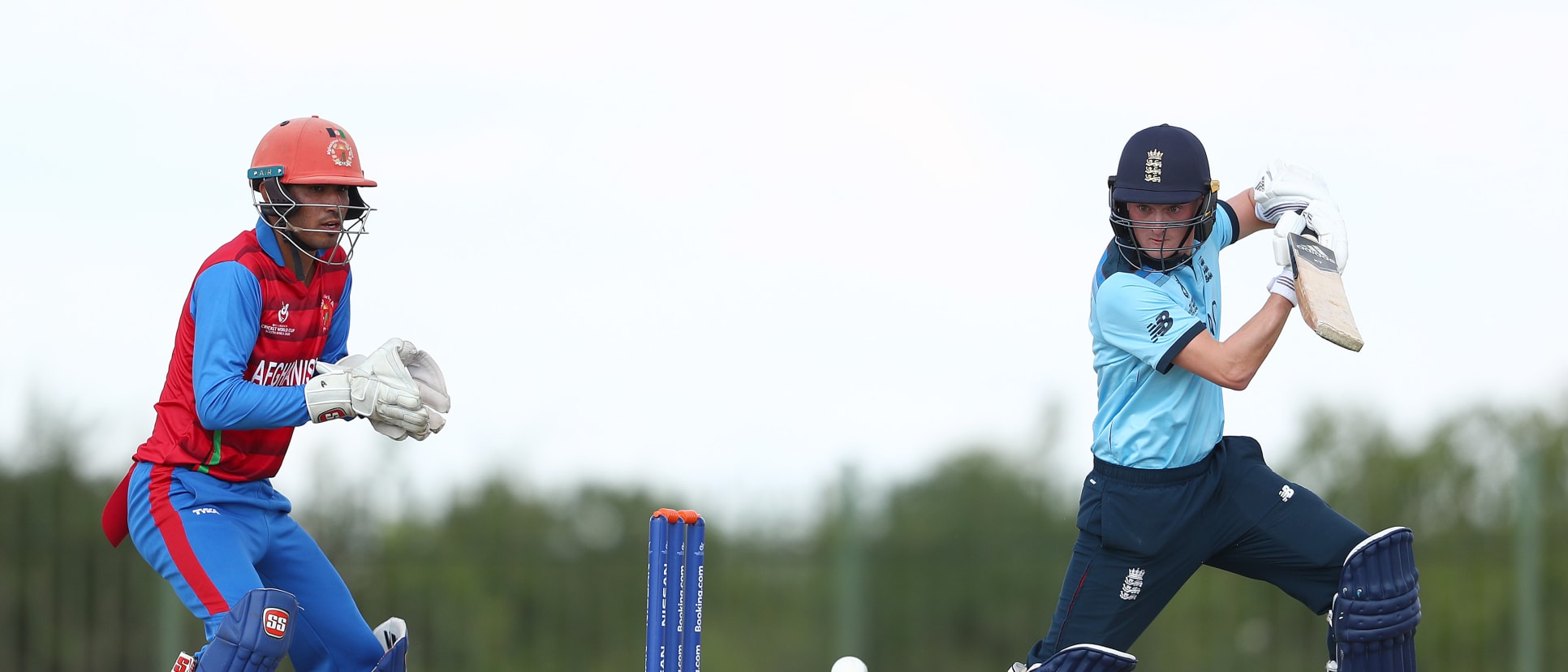 Lewis Goldsworthy of England hits the ball towards the boundary, as Mohammad Ishaq Shirzad of Afghanistan looks on during the ICC U19 Cricket World Cup warm up match between England and Afghanistan at Mandela Cricket Oval on January 14, 2020.