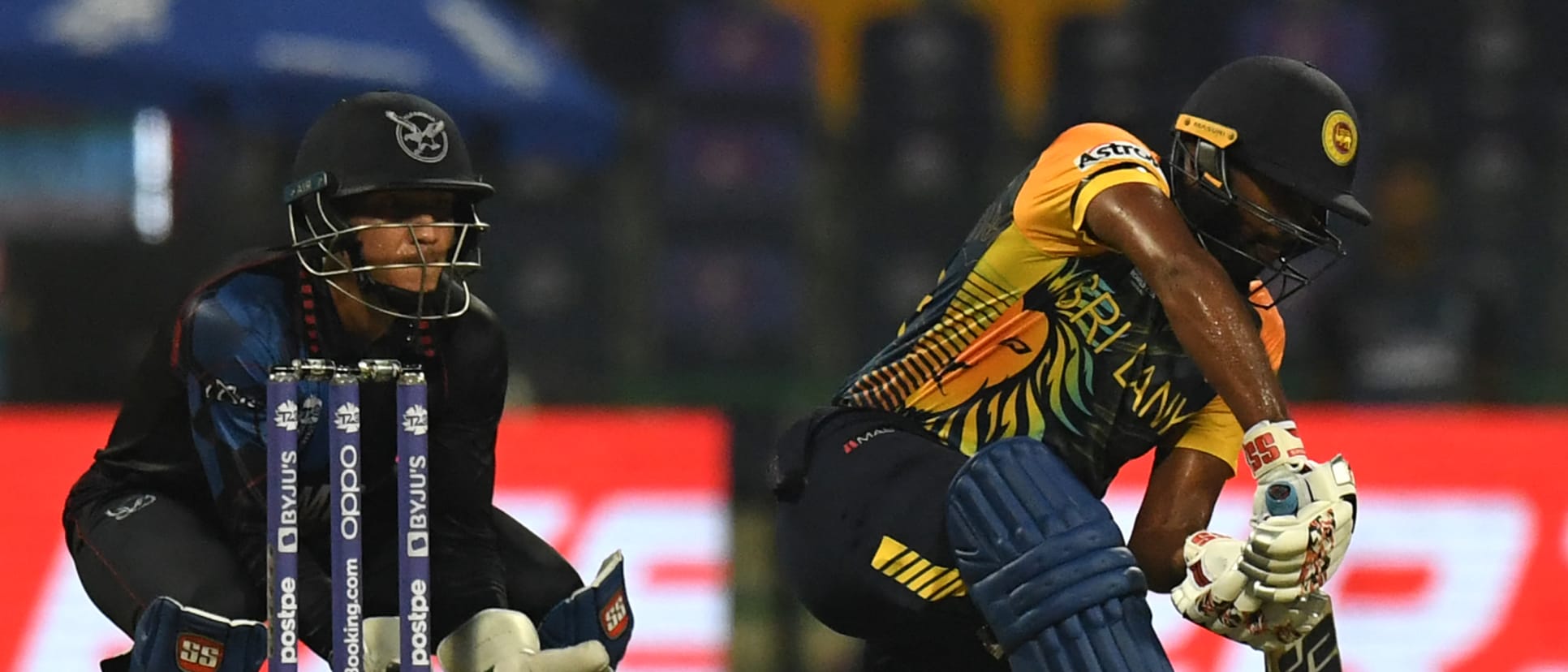 Bhanuka Rajapaksa (R) plays a shot as Namibia's wicketkeeper Zane Green watches during the ICC mens Twenty20 World Cup cricket match between Namibia and Sri Lanka at the Sheikh Zayed Stadium in Abu Dhabi on October 18, 2021.