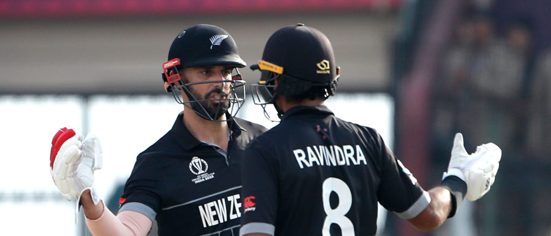 Daryl Mitchell (L) and Rachin Ravindra of New Zealand interact during the ICC Men's Cricket World Cup India 2023 match between India and New Zealand